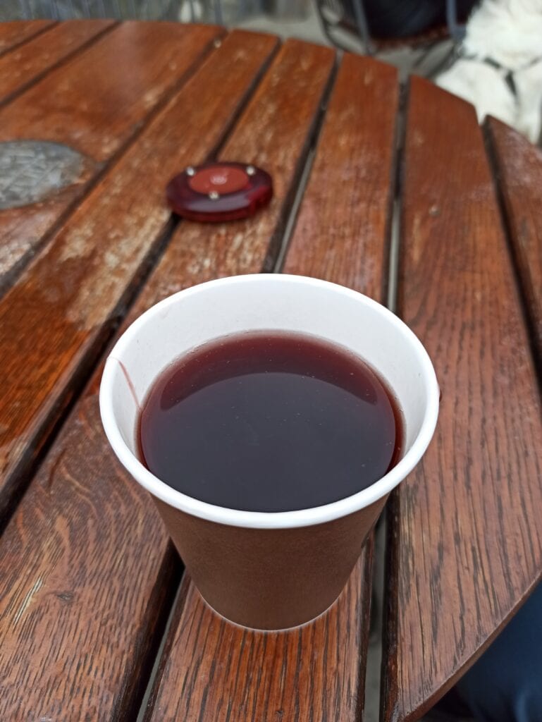 Grzaniec w tekturowym kubku stoi na stole na tarasie schroniska pod Biskupią Kopą.