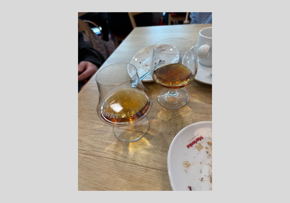 Dwa kieliszki z brandy obok talerzyków na drewnianym stole