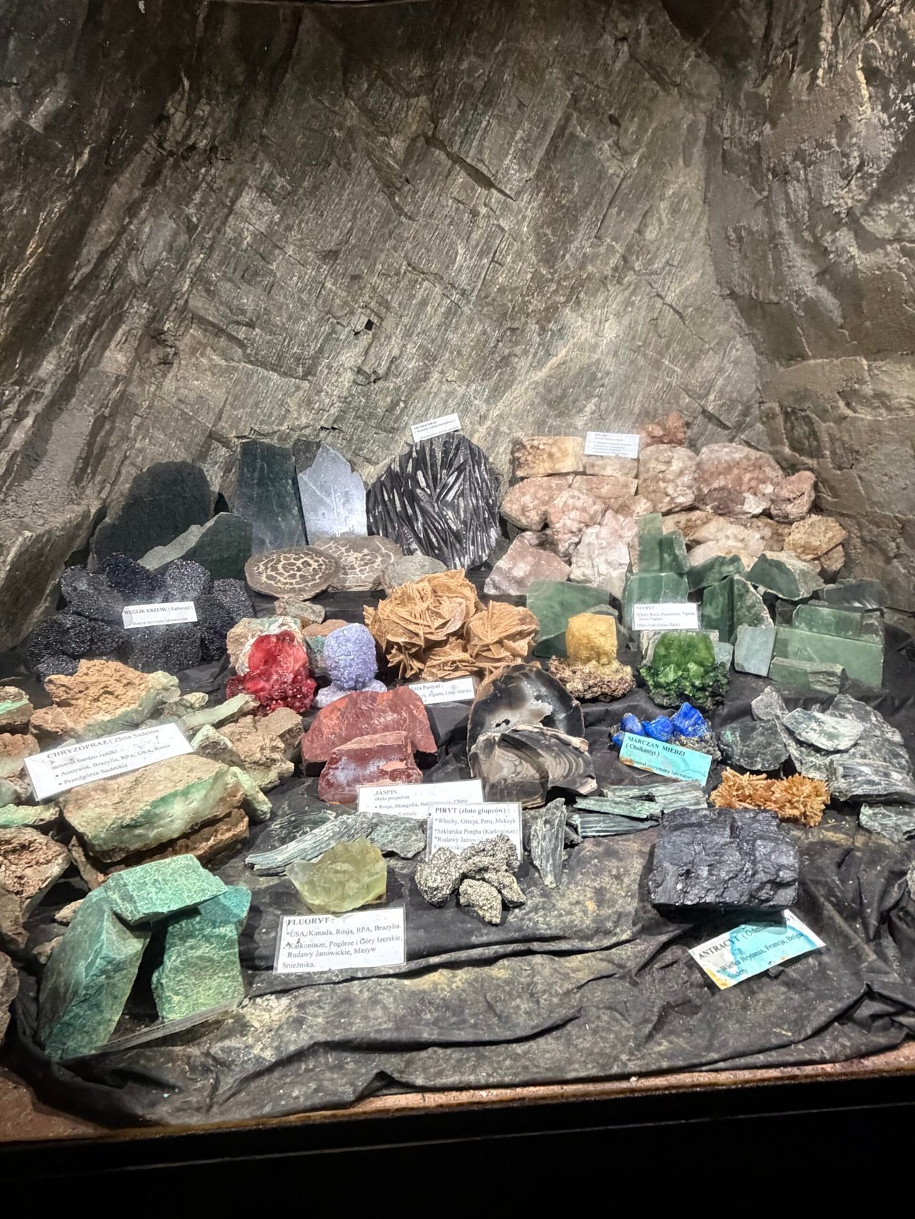 Kolekcja minerałów na tle skalnej ściany