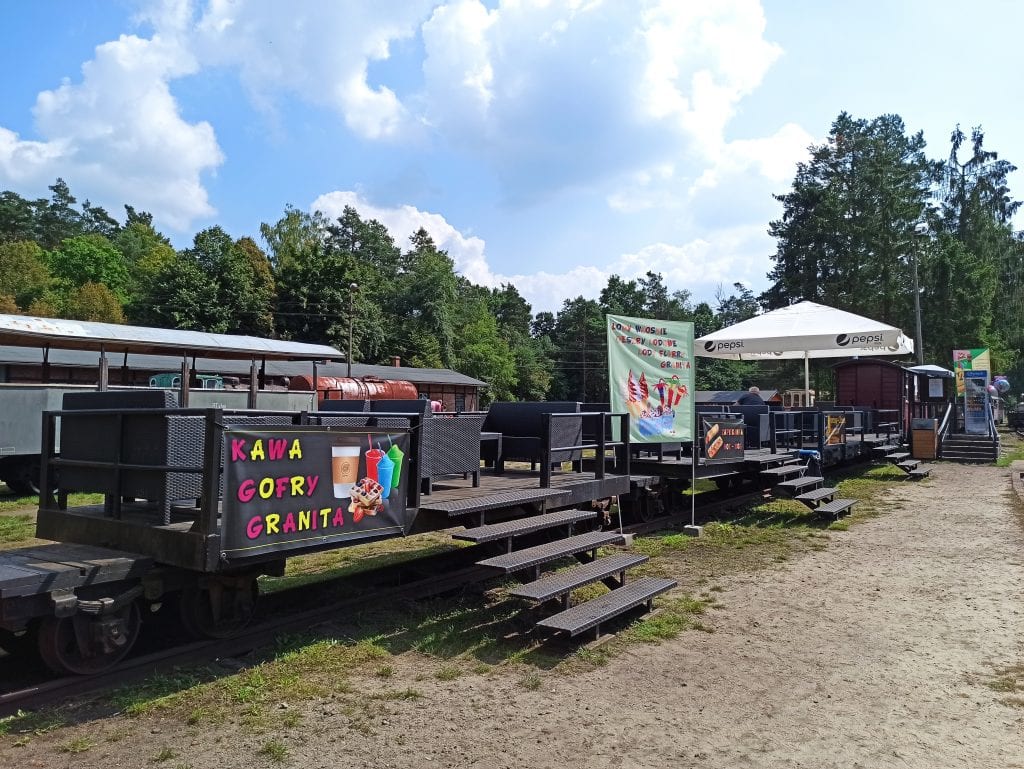 Dawny pociąg z odkrytymi wagonami zaadaptowany na punkt gastronomiczny.