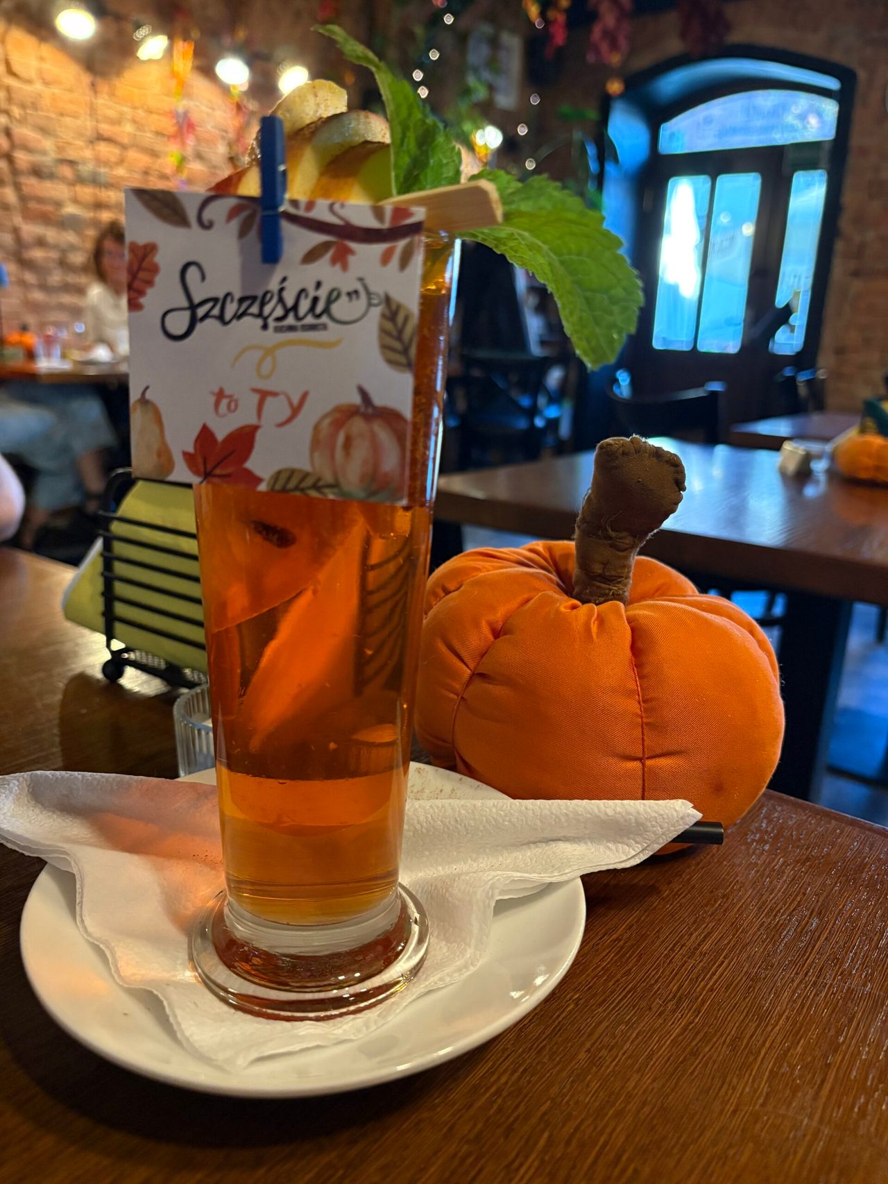 Wysoka szklanka z aperolem i pluszowa dynia na stole w restauracji