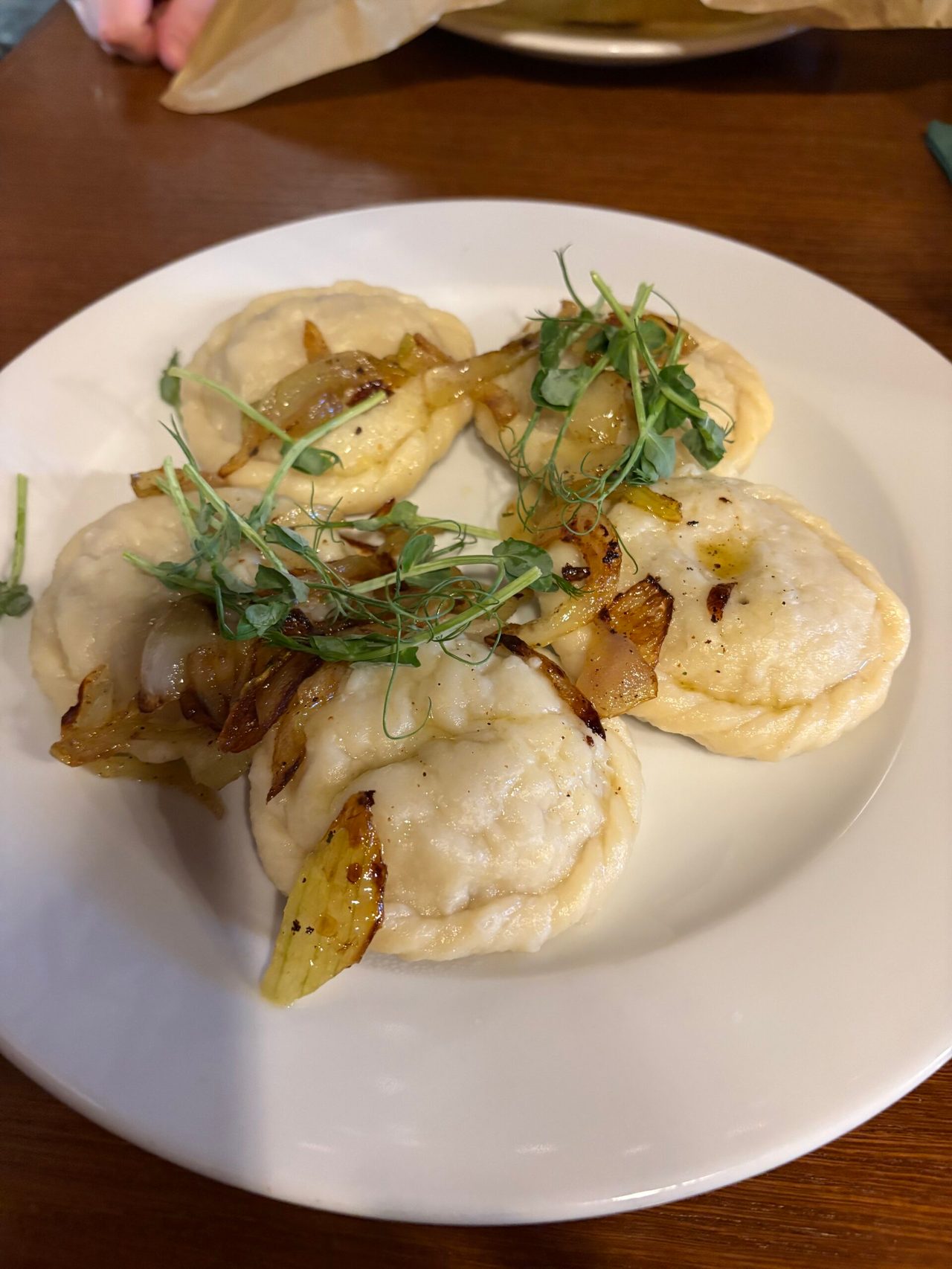Pięć dużych pierogów na białym talerzu