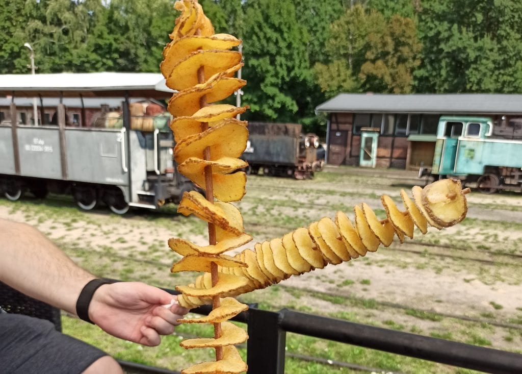 Zakręcony ziemniak, w tle Zabytkowa Stacja Kolejki Wąskotorowej w Rudach.